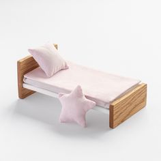 a wooden bed with two pink pillows and a star shaped pillow on the top of it