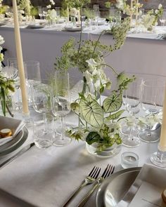 the table is set with silverware and white flowers