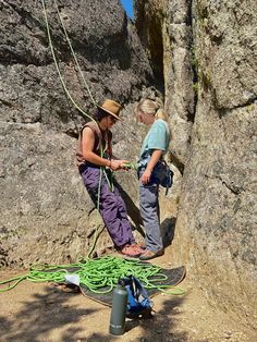 two people standing on top of a rock next to a climbing rope with ropes hanging from it