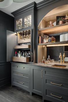 a kitchen with gray cabinets and marble counter tops, gold pulls on the cupboards