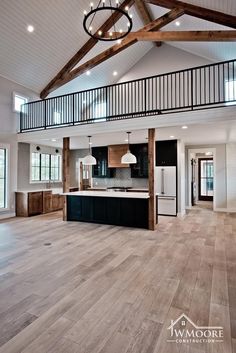 an open concept kitchen and living room with wood flooring, white walls and beams