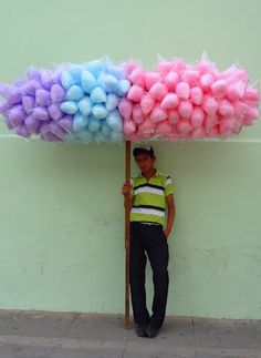 a man is standing under an umbrella made out of balls and tissue pom poms