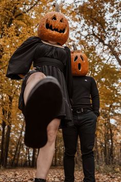 two people dressed up in halloween costumes with pumpkins on their heads and hands, standing next to each other