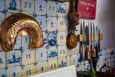 there are many knives on the wall next to each other in this kitchen area with blue and white tiles