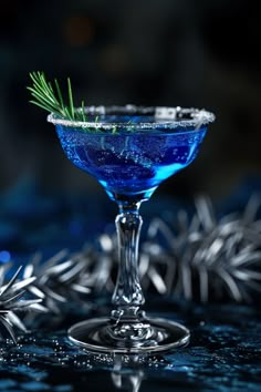 a blue cocktail in a martini glass with a sprig of rosemary