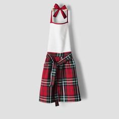 a red and white plaid dress with a bow on the back, hanging from a hanger