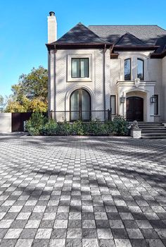 a large brick driveway in front of a white house