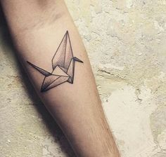 a small tattoo on the arm of a man with an origami bird in it