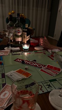 a person sitting at a table in front of a bottle of alcohol and some cards