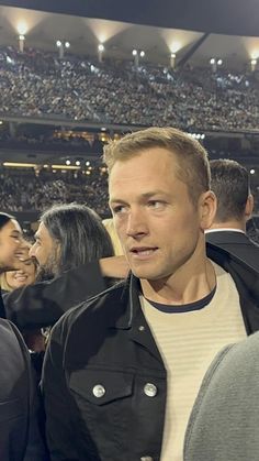 a man standing in front of a crowd at a baseball game with his eyes closed