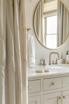 a bathroom with a large round mirror above the sink and gold faucet on the wall