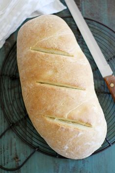 a loaf of bread sitting on top of a wire rack with a knife next to it