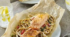 a plate with some noodles and salmon on it, next to two glasses of water