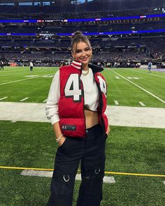 a woman standing on top of a field wearing a red and white football jersey with the number 4 on it