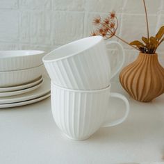 white dishes and vases are sitting on a countertop next to each other,