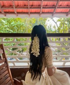 a woman sitting on top of a wooden bench wearing a white dress with flowers in her hair