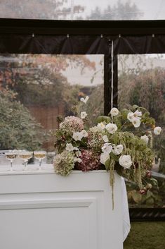 flowers and greenery are on display in front of a window at a wedding reception