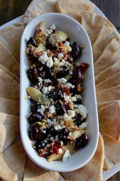 an appetizer dish with olives, feta cheese and pita chips