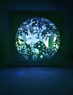 a paper cut artwork depicting mushrooms in the forest at night with blue light coming from behind