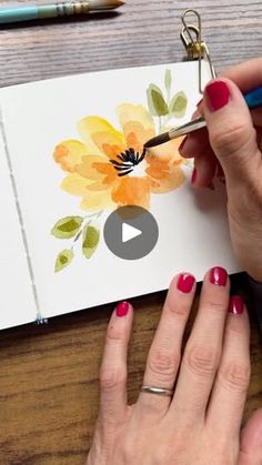 a woman is using scissors to paint flowers on a card