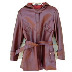 Vintage Faux Leather Jacket With Belt. Womens vintage size 18. Please see measurements below for fit. Burgundy/Brown faux leather. Hood. Quilted Lining. Two side pockets. Snaps all the way up the front. Leather look ladies coat made by Kmart. Shoulder to shoulder measures approximately 17". Shoulder to hem measures approximately 30". Bust measures approximately 42" . Leather Jacket With Belt, 1970s Jacket, 70s Jacket, Ladies Coat, Faux Leather Belts, All The Way Up, Faux Leather Jackets, Vintage 1970s, Vest Jacket