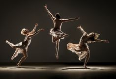 three dancers in motion with their arms outstretched