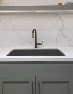 a kitchen sink under a mirror next to cabinets