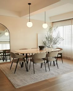 a dining room table with six chairs and a rug on the floor in front of it