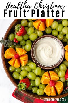 a bowl filled with fruit and dip surrounded by grapes, oranges, strawberries