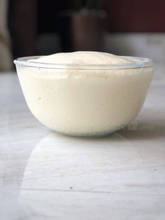 a glass bowl filled with cream sitting on top of a table