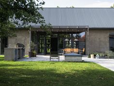 an outdoor kitchen and dining area is shown in the foreground, surrounded by green grass