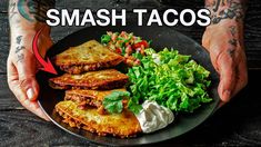 a person holding a plate with food on it and the words smash tacos in front of them