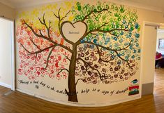 a large wall mural in the shape of a tree with hearts and words painted on it