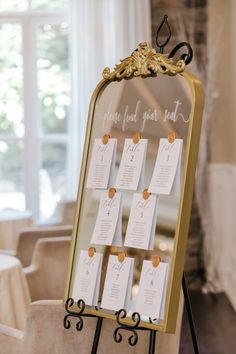 a gold mirror with seating cards attached to it