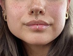 a close up of a woman with piercings on her nose, wearing gold hoop earrings