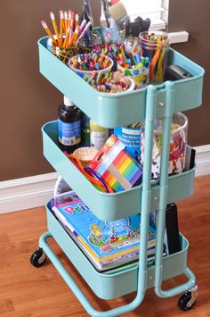 a blue cart filled with lots of school supplies on top of a hard wood floor