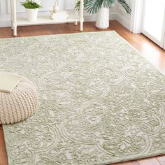 a white rug with a green pattern on it in a living room next to a potted plant