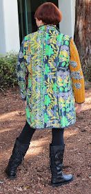 a woman standing in front of a tree with her back to the camera, wearing boots