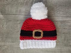 a crocheted santa hat with a gold buckle on it and a white pom - pom