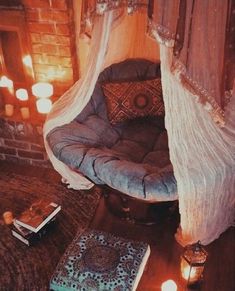 a bed with a canopy over it sitting on top of a wooden floor next to candles