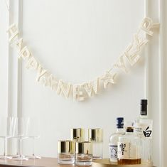 a happy new year banner hanging on the wall next to liquor glasses and an empty bottle