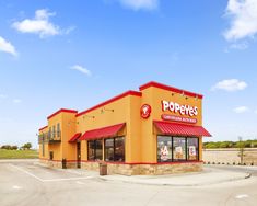 an empty parking lot in front of a poppet's restaurant with red and yellow awnings