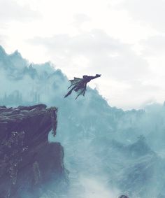 a man flying through the air while standing on top of a cliff next to a giant bird