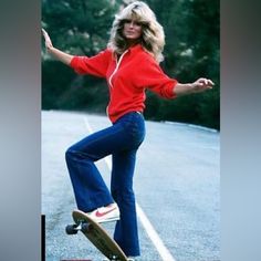 a woman riding a skateboard down the side of a road with trees in the background