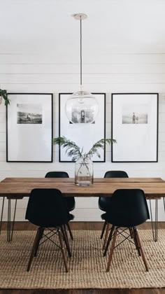 a dining room table with black chairs and pictures on the wall above it, in front of