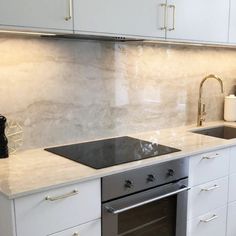 a kitchen with white cabinets and marble counter tops, an oven and dishwasher