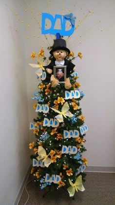 a teddy bear is sitting on top of a christmas tree with dad's day decorations