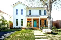 a large white house sitting next to a tree in front of a green door and window