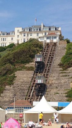 people on the beach with umbrellas and steps leading up to an ocean side resort