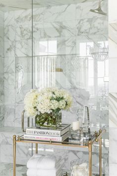 a bathroom with marble walls and white flowers in a vase on the shelf next to it